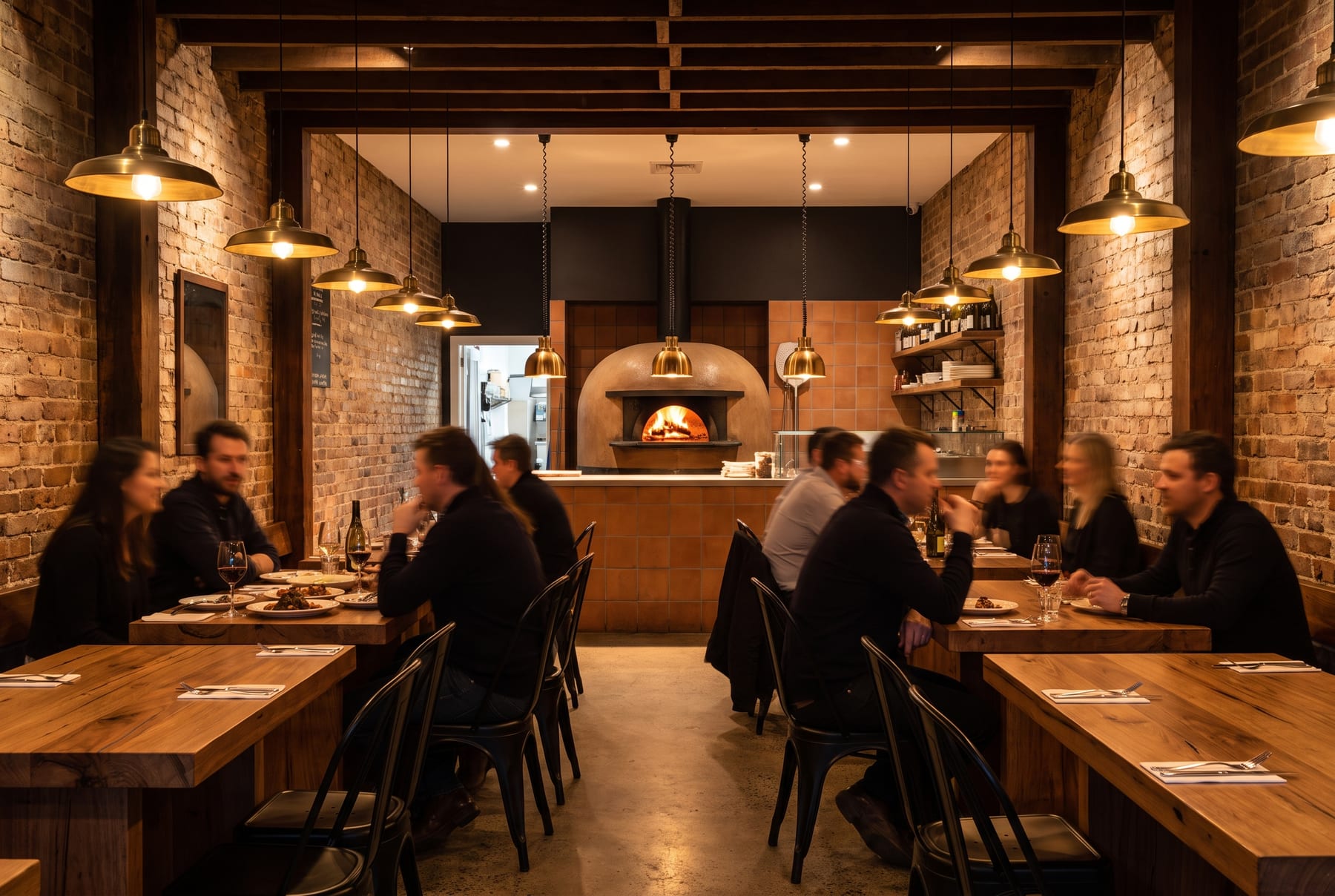 Interiorul pizzeriei FUMO seara, mese de lemn și cuptorul pe lemne aprins în fundal
